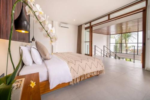 Schlafzimmer mit einem Bett mit weißer Bettwäsche und Kissen in der Unterkunft BaliMood Luxury 3BDR Ocean View in Canggu