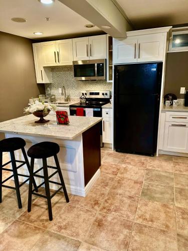 a kitchen with a black refrigerator and two bar stools at The Oasis@Woodyard in Upper Marlboro