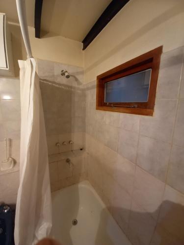 a bathroom with a tub with a window and a television at La casa de Ana in Ushuaia