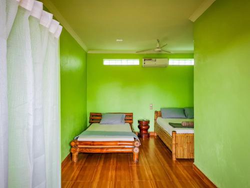 um quarto verde com duas camas e uma janela em Steng Toch Homestay em Phumĭ Bântéay Srei