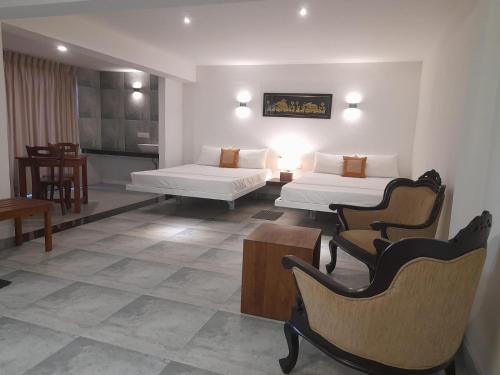 a hotel room with two beds and a table and chairs at Lotus Lake Residence in Kandy