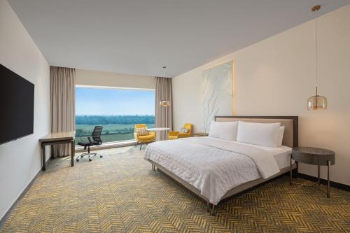 a hotel room with a bed and a desk and chair at Le Meridien Nagpur in Nagpur