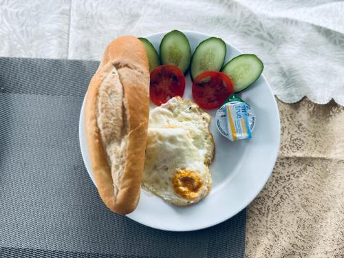 a plate with an egg sandwich and vegetables on it at Cat Ba Seoul 2 Hotel & Apartment in Cat Ba