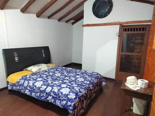 ein Schlafzimmer mit einem Bett mit einer blauen und weißen Decke in der Unterkunft Casona la Vega in Pasto