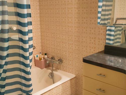 La salle de bains est pourvue d'une baignoire et d'un rideau de douche. dans l'établissement Maison familiale près de la mer avec terrasse et véranda, quartier calme à Saint Jean de Monts - FR-1-323-502, à Saint-Jean-de-Monts