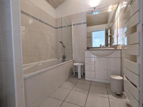 une salle de bain blanche avec une baignoire et un lavabo dans l'établissement Duplex T3 lumineux à Arcachon avec balcon, parking, Wi-Fi à 5 min de la plage et des commerces - FR-1-420-140, à Arcachon