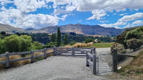 a gate on a road with mountains in the background at Tucker Beach Private Exclusive Retreat in Queenstown