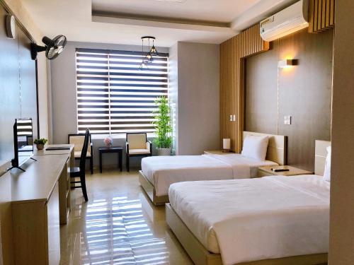 Habitación de hotel con 2 camas y escritorio en Khách sạn 20-10 Quảng Bình, en Dong Hoi