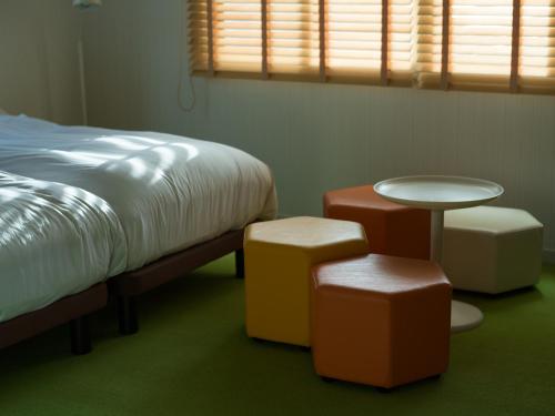 a bedroom with a bed and a table and stools at Holiday House Green Garden in Gujo