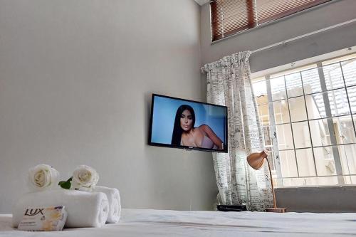 a tv hanging on a wall in a bedroom at Cozy Hatfield Condo in Pretoria