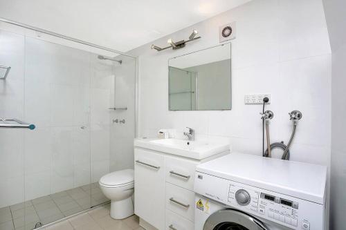 a white bathroom with a sink and a washing machine at Loftstyle One Bedroom in the Heart of CBD SX504 in Sydney