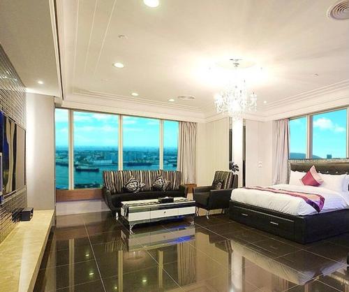 a bedroom with a bed and a couch and a table at Neo Sky Hotel in Kaohsiung
