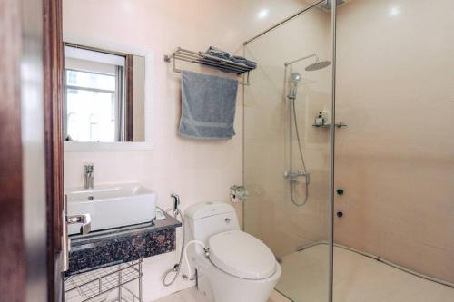 La salle de bains est pourvue de toilettes, d'un lavabo et d'une douche. dans l'établissement Sunset Pool Villa 4BR, New, Full AC, walk to beach, à Đà Nẵng