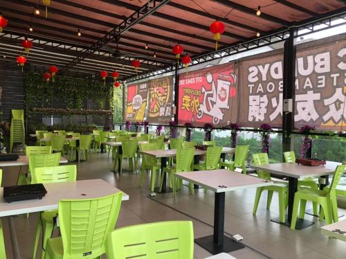 a restaurant with green tables and chairs and a wall at SL TR Homstay in Cameron Highlands