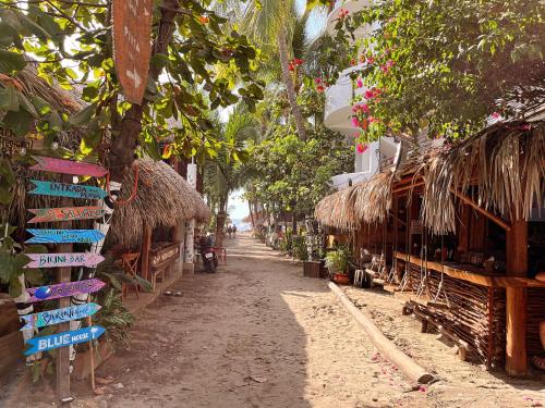 uma rua com um grupo de cabanas de palha e um sidx de rua em Blue House em Puerto Escondido