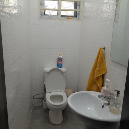 a white bathroom with a toilet and a sink at Chateau Eyram in Accra