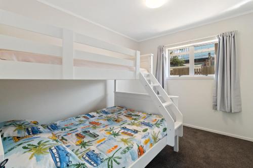 ein Schlafzimmer mit einem Etagenbett und einer Leiter in der Unterkunft Barefoot Breeze - Waihi Beach Holiday Home in Waihi Beach
