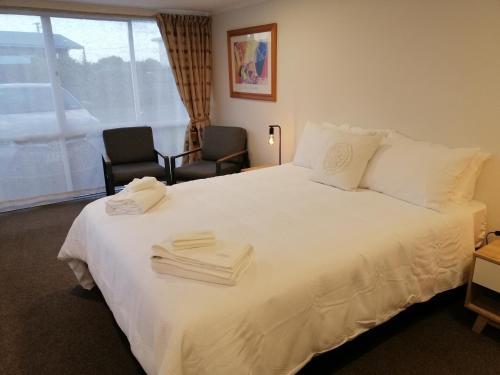 a bedroom with a white bed with two towels on it at Reeves Retreat-Handy in Tasman in Nelson