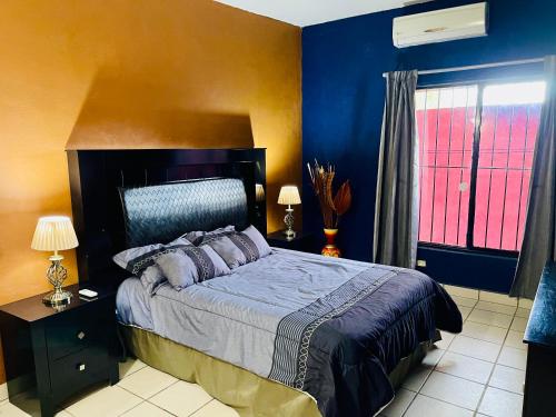 Schlafzimmer mit einem Bett mit blauen Wänden und einem Fenster in der Unterkunft Casa El Pescador in Mulegé