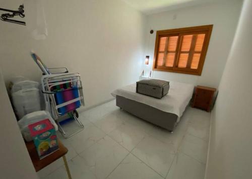 um pequeno quarto com uma cama e uma janela em Aconchego da praia em Capão da Canoa