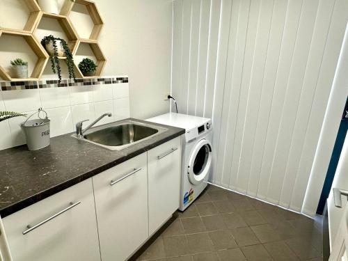 a kitchen with a sink and a washing machine at Villa 2 Dunsborough Villas in Dunsborough