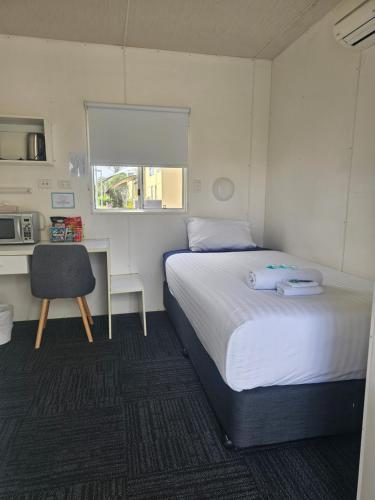 a bedroom with a bed and a desk and a chair at Hive Hotel, Moruya in Moruya