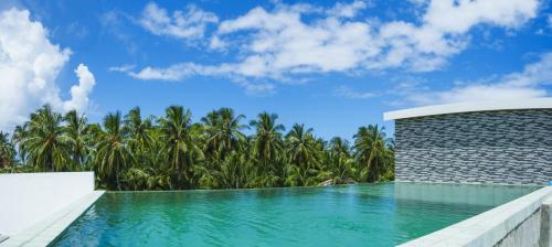 a swimming pool in a resort with palm trees at The Shark Residence in Fuvahmulah