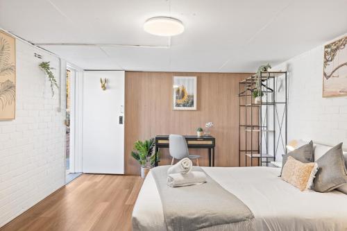 a white bedroom with a large bed and a desk at Premier Leichhardt Stayz in Sydney