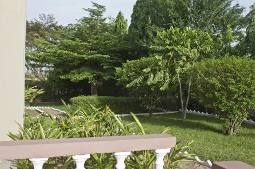 a bench in a garden with trees and grass at Four Villages Inn in Kumasi