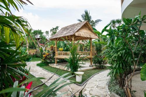 a wooden gazebo with a bench in a garden at Shanti Boutique Retreat in Tanah Lot