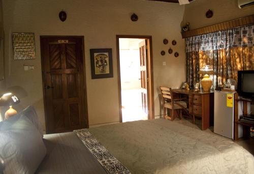 a bedroom with a bed and a desk and a kitchen at Four Villages Inn in Kumasi