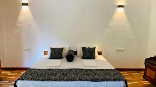 a bedroom with a large bed with two pillows at Sigiriya Chena Villa in Sigiriya