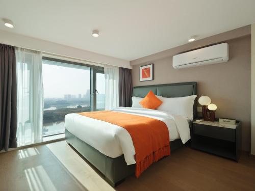 East Maple Hotel Apartment - Guangzhou Financial City Sanxi Metro Station في قوانغتشو: غرفة نوم بسرير كبير ونافذة كبيرة