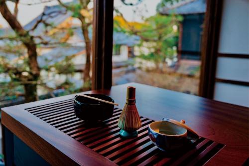 a wooden table with two bowls and a bottle on it at Kagetsu Taisyokan in Takeo