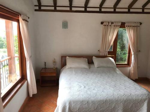 1 dormitorio con 1 cama blanca y 2 ventanas en Casa campestre - Villa de Leyva, en Villa de Leyva