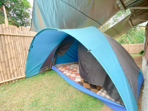 a blue tent sitting in the grass next to a fence at Villa Bamboe in Puncak