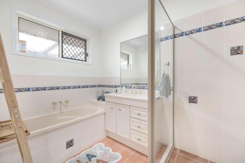 a bathroom with a tub and a sink and a shower at 'Hygge' Family-Friendly Comfort in Hervey Bay in Hervey Bay