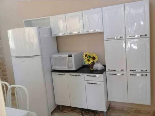 a kitchen with white cabinets and a microwave at Sítio Vô Chico. in Mauá