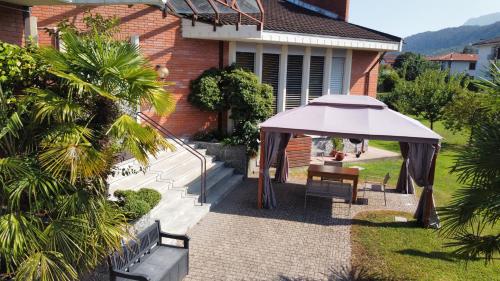 eine Terrasse mit einem Sonnenschirm, einem Tisch und einer Bank in der Unterkunft Casa vacanze LILLY in Germignaga