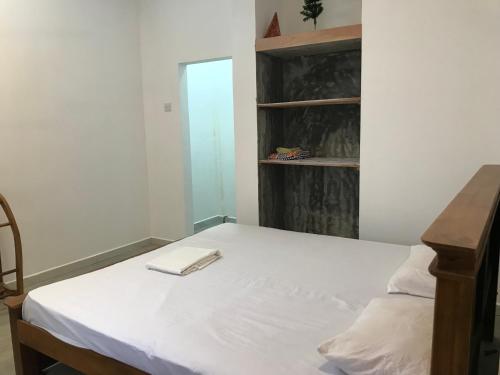 1 dormitorio con cama blanca y estante para libros en One Bed Room Apartment, en Weligama