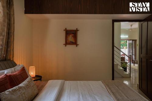 a bedroom with a bed and a picture on the wall at StayVista at Nature Nook with Pvt Pool & Terrace Access in Trichūr