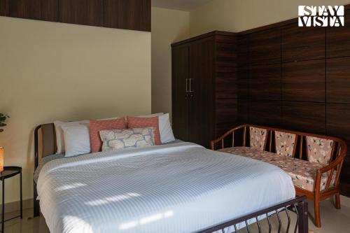 a bedroom with a bed and a chair in it at StayVista at Nature Nook with Pvt Pool & Terrace Access in Trichūr