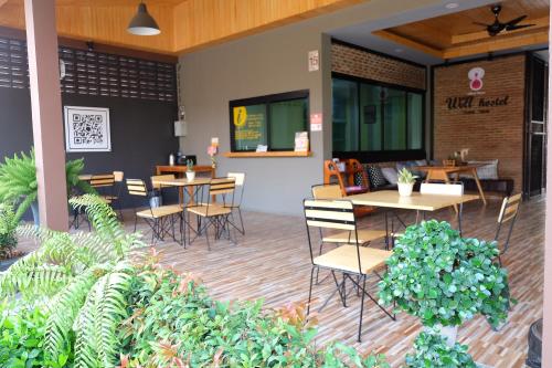 a restaurant patio with tables and chairs and plants at Warmwell Hostel in Ban Chuk Kum