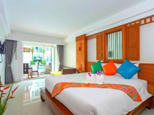 a bedroom with a large white bed with colorful pillows at The Samui Beach Resort in Koh Samui