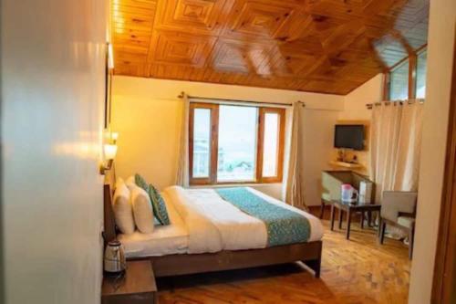 a bedroom with a bed with a window and a desk at OYO Banka Guest House in Manāli