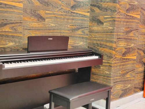 a piano with a bench next to a wooden wall at Skytree A0902-(1) in Foodie City in Johor Bahru