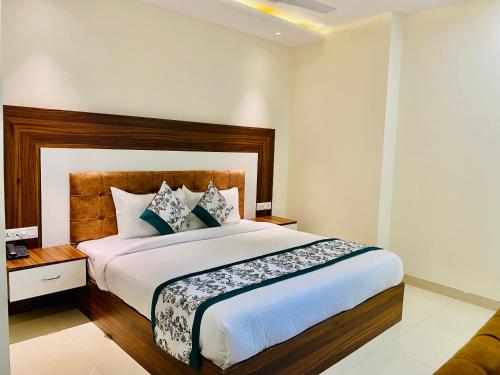 Schlafzimmer mit einem großen Bett mit einem Kopfteil aus Holz in der Unterkunft Hotel White house near Golden Temple in Amritsar