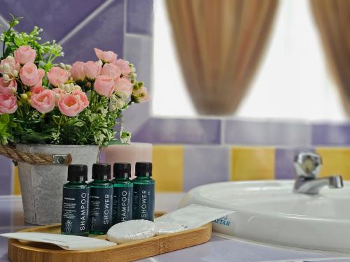 un mostrador de baño con 2 botellas de jabón y flores en Cottage Inn Gerik, en Gerik