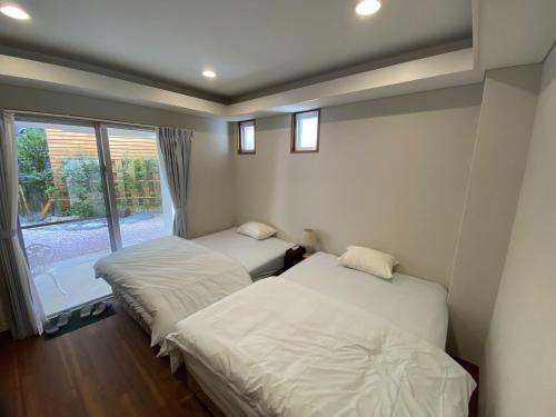 dwa łóżka w pokoju z oknem w obiekcie Vacation Rental Kally Naha Okinawa w mieście Naha