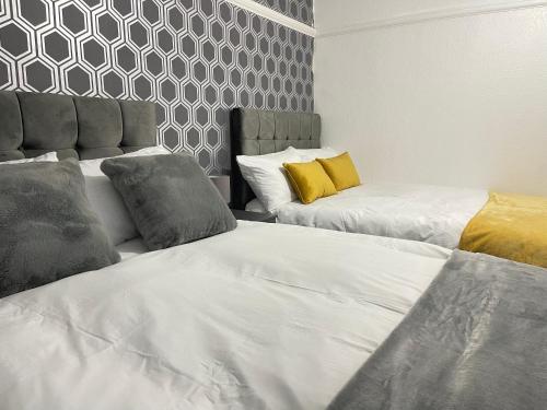 two beds sitting next to each other in a room at Easystays The Hidden Gem Large Basic Home Can Sleep 15 in Braunstone